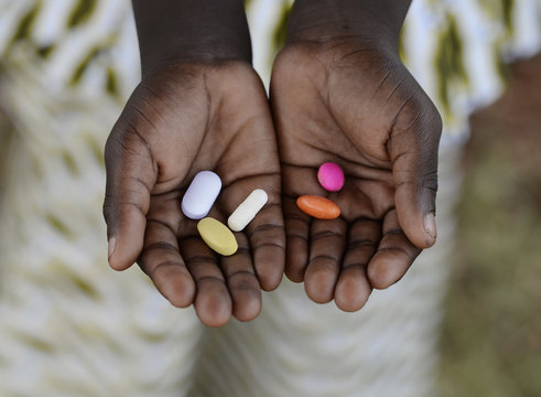 Healthy Lifestyle Medicine African Black Boy Holding Colorful Pills Background. Unfortunately, in Africa there are lots of diseases like malaria, pneumonia, AIDS or simple Diarrhoea. 