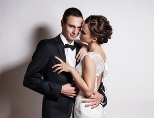 Portrait of young couple in love posing at studio dressed in classic clothes
