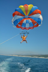 Father and son fly on a parachute over the sea