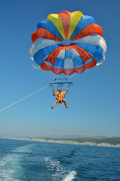 Father and son fly on a parachute over the sea