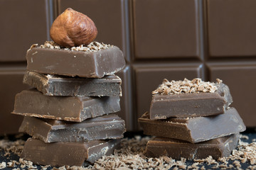 Milk chocolate with hazelnut. Black base, brown chocolate in the background.