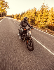 Obraz premium Siedzenie człowieka na motocyklu na drodze w lesie.