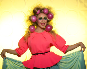 Cheerful girl with bright makeup and hair balls on a yellow background