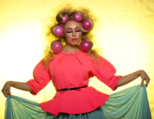 Cheerful girl with bright makeup and hair balls on a yellow background