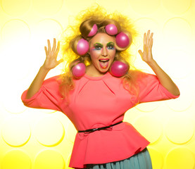 Cheerful girl with bright makeup and hair balls on a yellow background