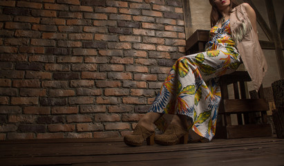 Naklejka premium young sensual woman sitting on chair on old brick wall backgroun