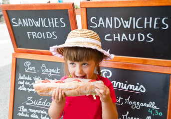 young girl eating a big sandwich