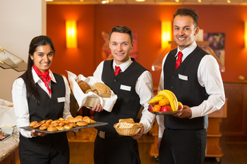 Waitress and waiters posing with food at buffet in a restaurant