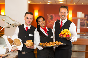 Waitress and waiters posing with food at buffet in a restaurant