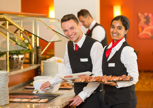 Catering service employees filling buffet at restaurant or hotel