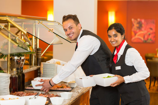 Catering service employees filling buffet in restaurant