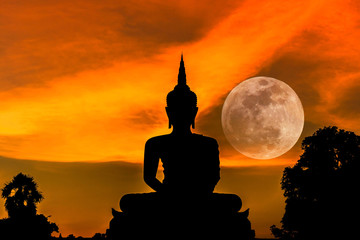 silhouette big buddha statue sitting on sunset with full moon background