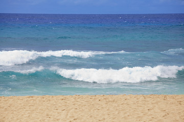 Fototapeta na wymiar Blue waters and waves on a Hawaiian beach on sunny day