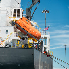 orange free-fall life boat for emergency crew evacuation installed on cargo ship