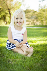 Fototapeta premium Cute Little Girl Sitting and Laughing in the Grass