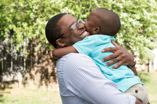 African American father and son hugging and laughing.