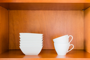 Fototapeta na wymiar Organized minimalistic kitchen cabinet with white porcelain bowl