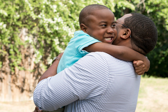 African American father and son hugging and laughing.