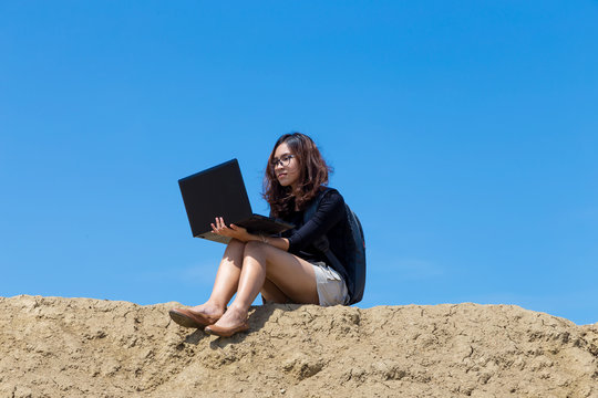 Young Woman Working With Laptop On The Mountain With Blue Sky Background