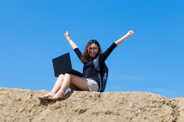 young woman working with laptop on the mountain with blue sky background