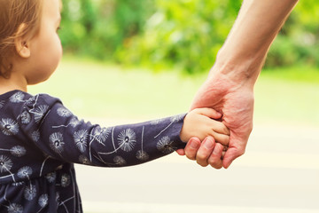 Toddler girl holding hands with her father