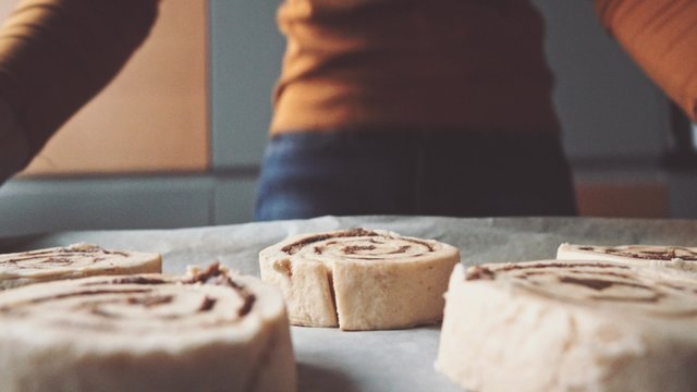 Point of view: cinnamon rolls being put into the hot oven. POV: woman baking sweet buns with cinnamon, putting them into the electrical stove. Home made bakery. Cozy Cooking at home kitchen. 4K. 