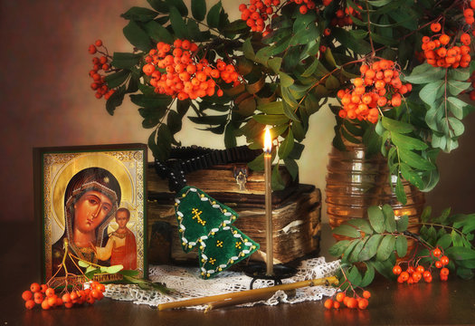 Religious still life with an icon of the Holy Mother and rowan tree branches