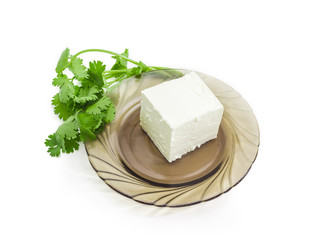 Feta cheese on a saucer and a branch cilantro