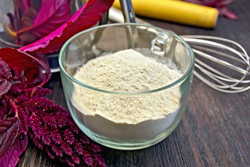 Flour amaranth in glass cup with rolling pin on board