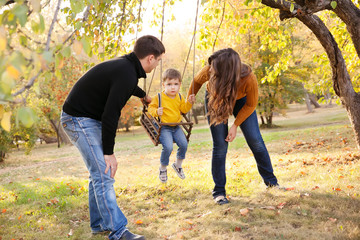 Happy family having fun on a swing ride at a garden a autumn day