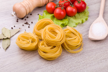 Pasta, tomatoes and pepper on a wooden background