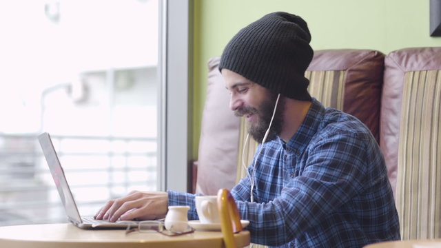 Young hipster fashion man working on laptop in coffee shop