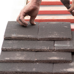 Man fitting roof tiles in rows