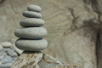 Fototapeta na wymiar Five sea stones Balanced on the Rock. Zen stones on rock background