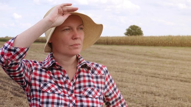 Concerned farmer planning new seeding season, female farmer with straw hat at cultivated field
