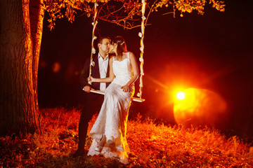 A beautiful married couple is swinging outdoors