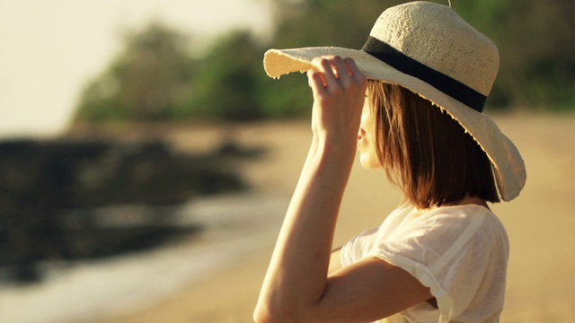 Woman with summer hat admire sunset on the beach, super slow motion
