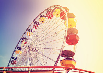 Old film retro style picture of a ferris wheel in an amusement park.