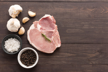 Top view raw pork chop steak and garlic, pepper, salt on wooden