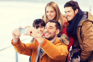 Fototapeta premium happy friends with camera on skating rink