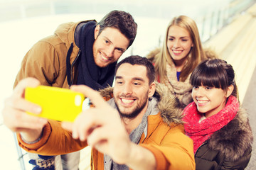 happy friends with smartphone on skating rink