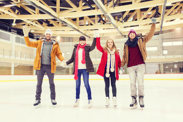happy friends waving hands on skating rink
