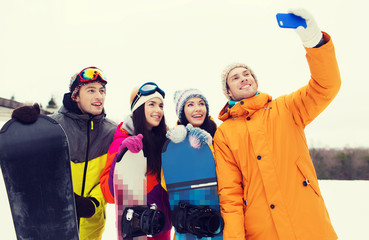 happy friends with snowboards and smartphone