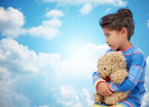 Sad Little Girl With Teddy Bear Toy Over Blue Sky