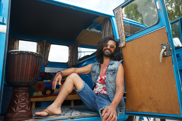 smiling young hippie man in minivan car
