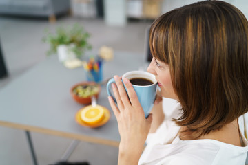 frau sitzt am schreibtisch und entspannt bei einer tasse kaffee