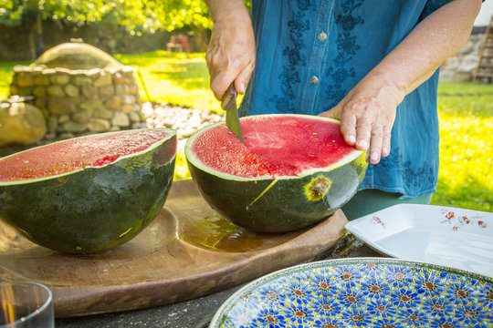 close up of a men who is cutting a water melon