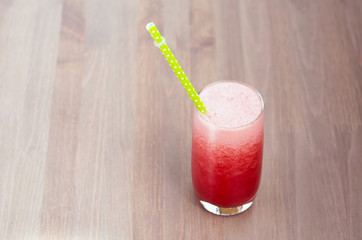 A glass of fresh watermelon smoothie on wooden background