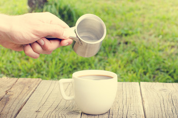 Hand with milk and cup of coffee