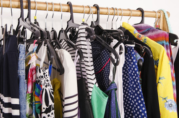Close up on colorful clothes on hangers in a store. Clothes and accessories hanging on a rack nicely arranged.